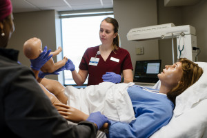 Nursing students and instructor working with simulated mother and infant patients